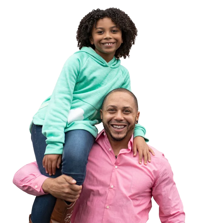 A smiling girl rides on her father’s shoulders