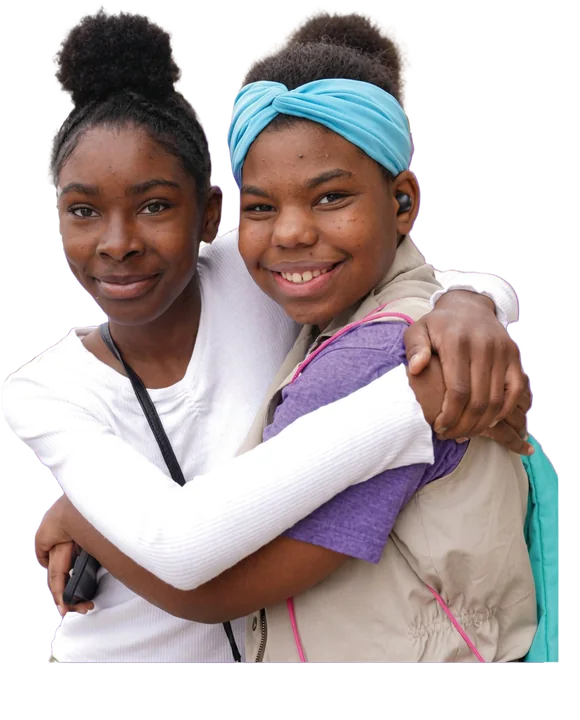 Two smiling Girl Scouts hug each other